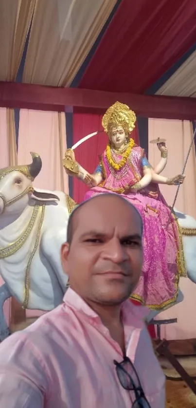 Man posing with festival statue in vibrant colors.