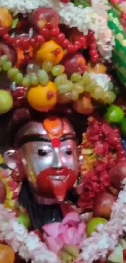 Deity decorated with fruits and flowers in vibrant festival style.