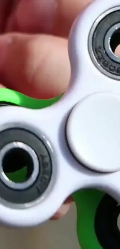 Close-up image of green-accented fidget spinner held in hand.