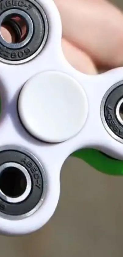 Vibrant green and white fidget spinner in hand.