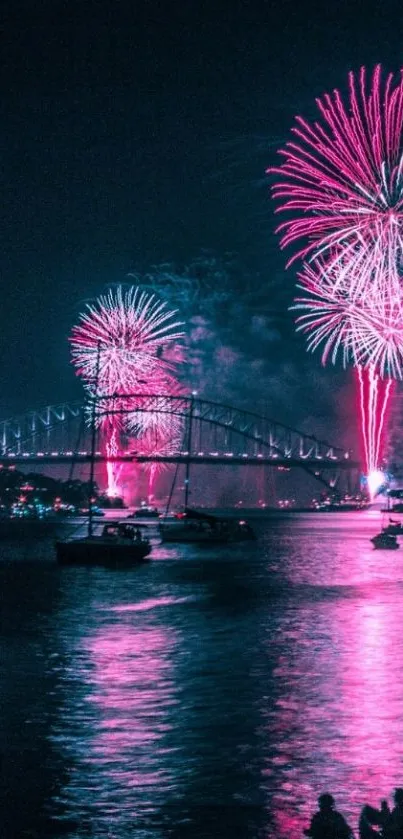 Brilliant pink fireworks explode over a nighttime bridge scene.