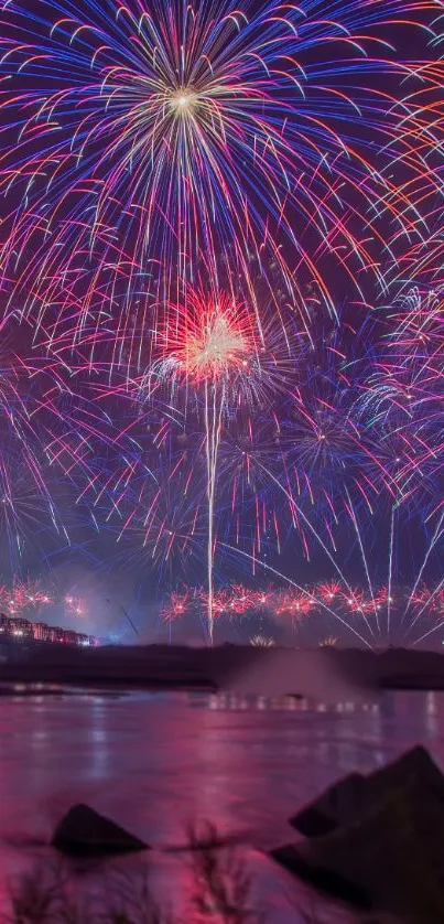 Stunning fireworks display over water at night with vibrant magenta hues.