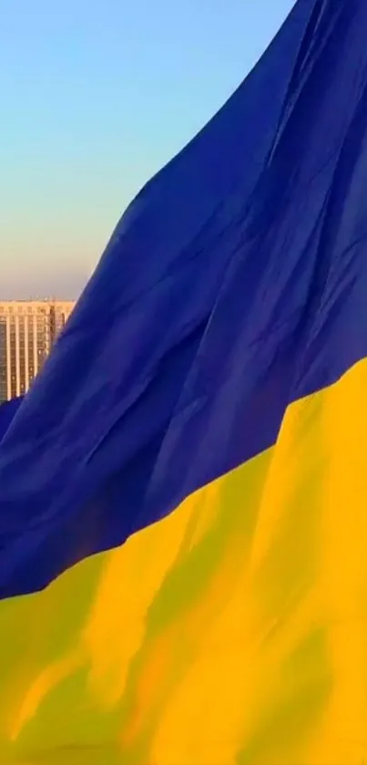 Vibrant flag against clear sky with urban skyline.