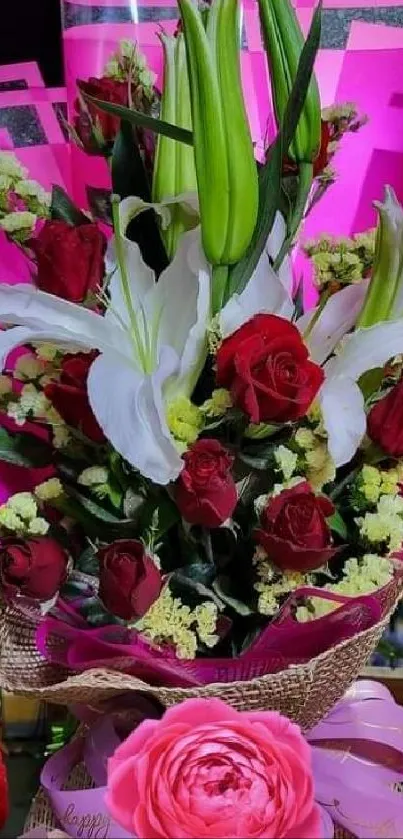 A vibrant flower bouquet with red roses and white lilies wrapped in pink.