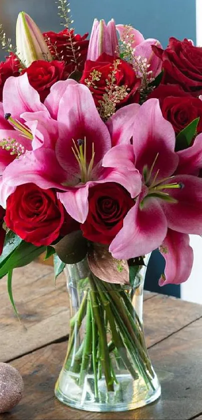 A vibrant floral bouquet with red roses and pink lilies in a glass vase.