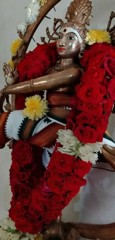 Deity adorned with vibrant red and white flowers.