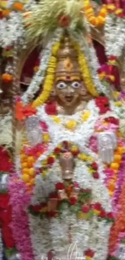 Deity statue adorned with vibrant floral garlands.