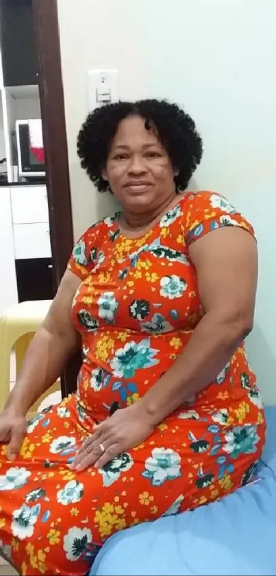 Woman in colorful floral dress on a cozy patterned wallpaper.