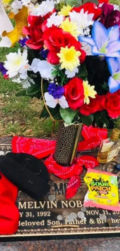 Vibrant floral memorial with mementos on a plaque.