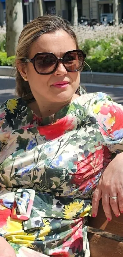 Woman in floral dress sitting on a bench outdoors.