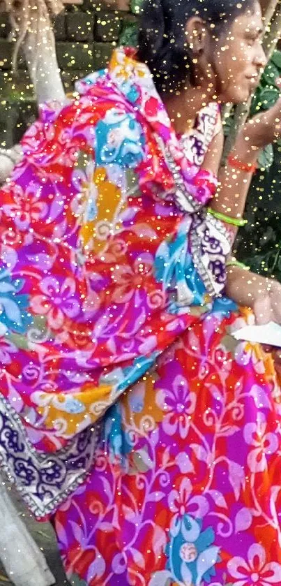 Woman wearing a colorful floral sari, seated outdoors.