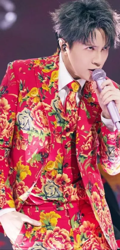 Performer in a vibrant floral suit sings passionately on stage with a lively background.