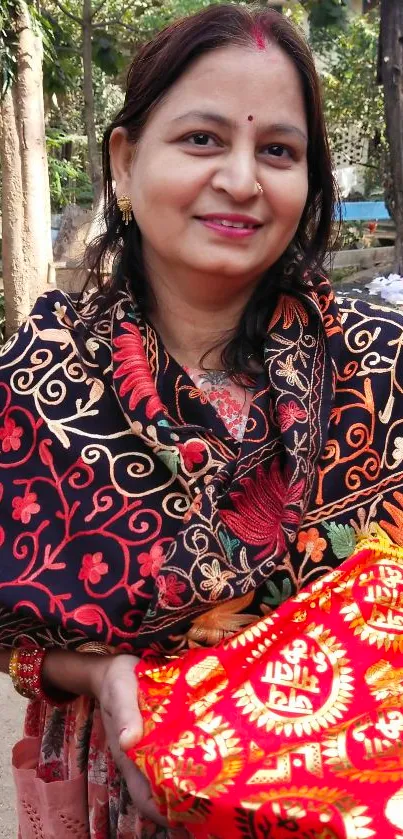 Woman in traditional attire holding vibrant floral fabric.