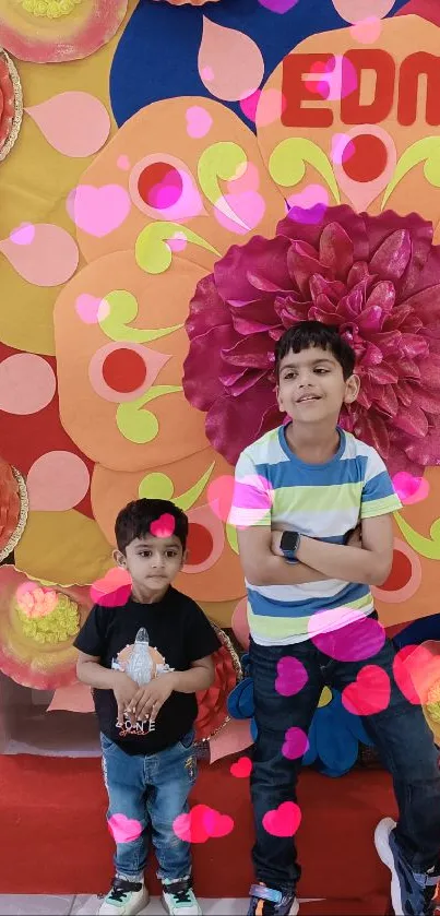 Colorful flower wall display with children posing in front.