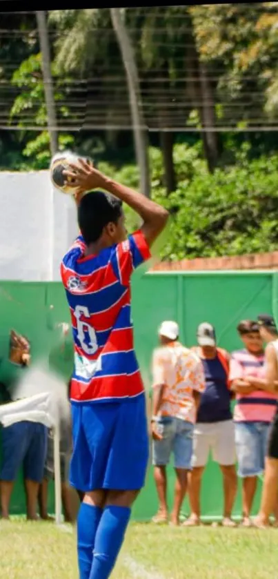 Player in blue and red jersey taking a throw-in on a green football field.