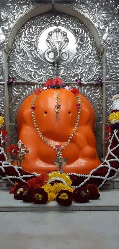 Orange Ganesh idol with ornate details and colorful decor.