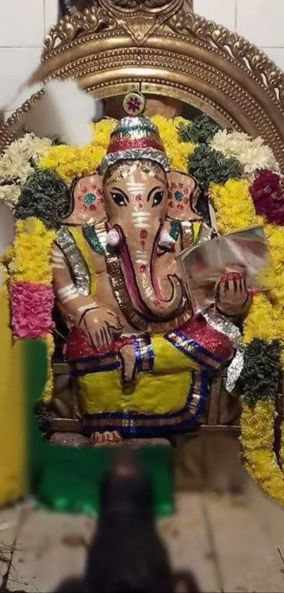 Ganesh idol with vibrant floral decor in worship setting.