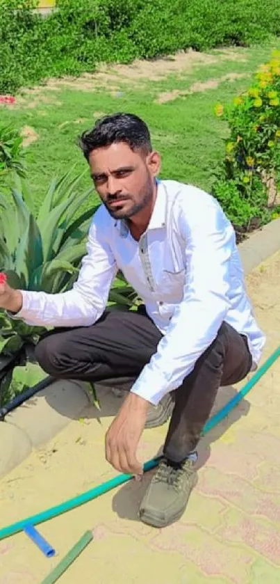 Man holding a flower in a vibrant garden setting.