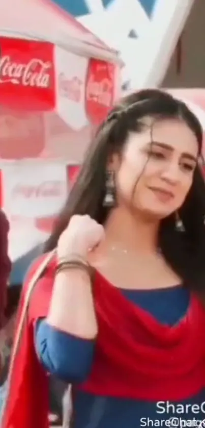 Woman in vibrant red and blue traditional attire smiling at a festival.