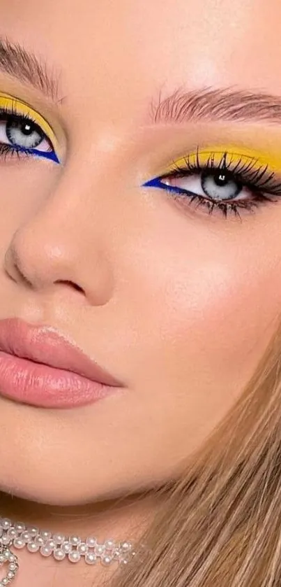 Mobile wallpaper featuring vibrant eye makeup with yellow and blue shades.