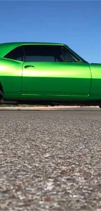 Vibrant green classic car on a road with clear blue sky.