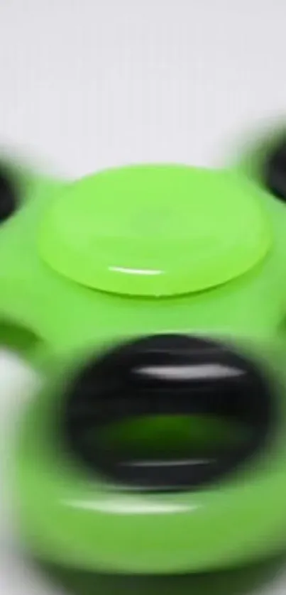 Vibrant green fidget spinner in motion on a minimalist background.