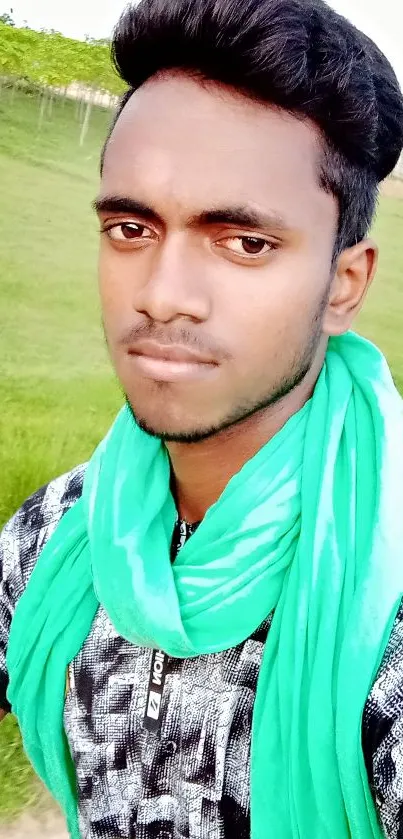 Man in vibrant green scarf outdoors, serene backdrop.