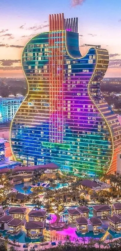 Colorful guitar-shaped building at sunset, reflecting vibrant hues.