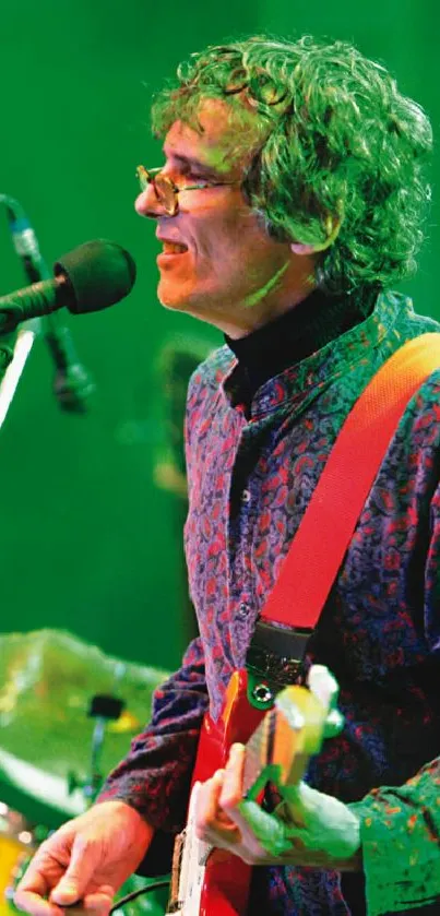 Guitarist performing live on stage with vibrant green lighting.