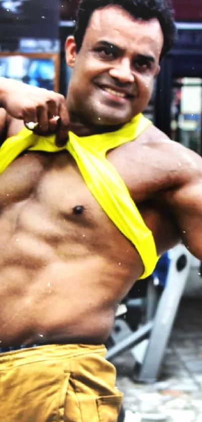 Man in yellow shirt showcasing muscles in gym setting.