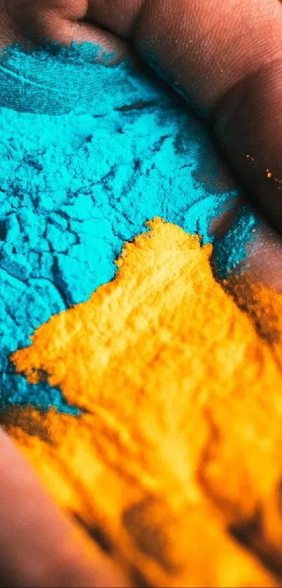 Hand holding vibrant blue and orange powder art design.