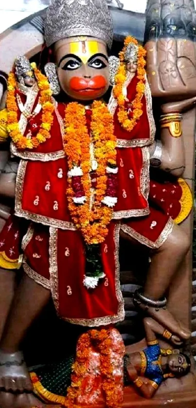 Vibrant Hanuman statue with floral garlands and intricate details in red and gold.