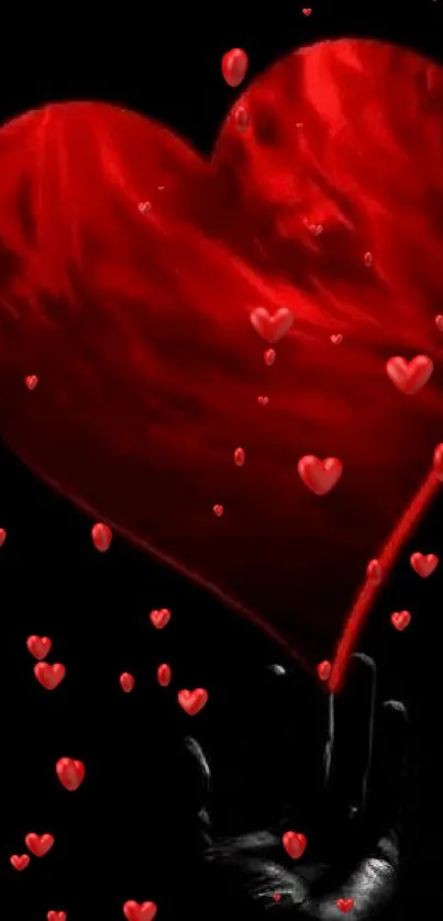 A vibrant red heart glowing against a black background, held by a dark hand.