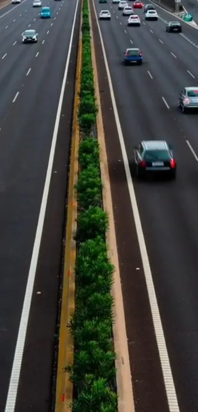 Aerial view of a busy highway with green median and several vehicles.