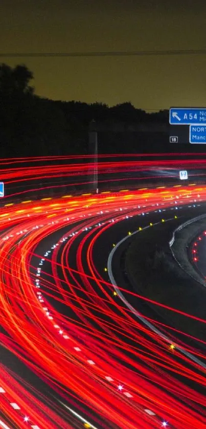 Dynamic red light trails on a highway at night with road signs visible.