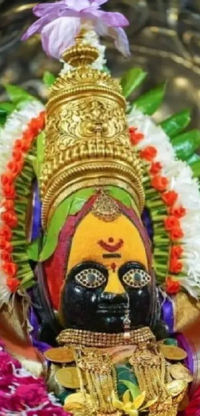 Colorful Hindu deity with gold jewelry and floral garlands.