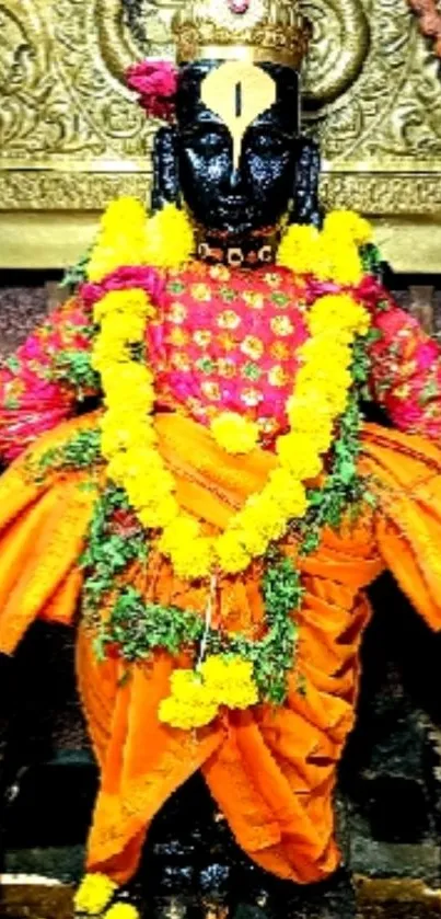 Hindu deity adorned in orange with yellow garlands.