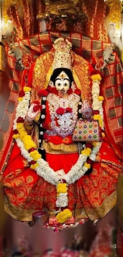 Hindu goddess in vibrant red attire with floral garlands and jewelry.