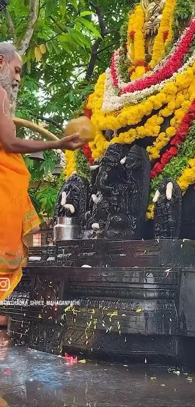 Hindu priest in orange robe performs ritual with floral decorations.