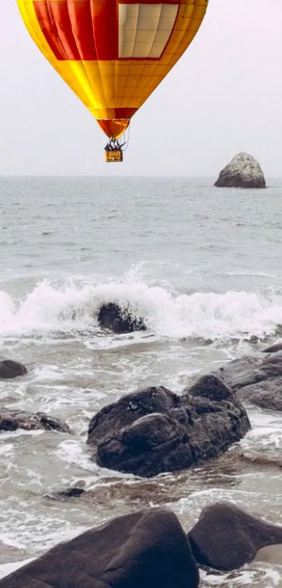 Hot air balloon over ocean with rocks and waves; vibrant and serene mobile wallpaper.