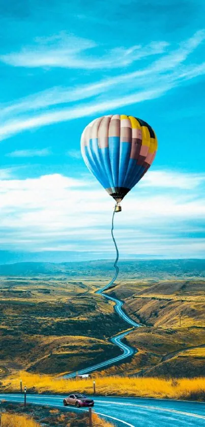 Hot air balloon over a winding road landscape with blue skies.