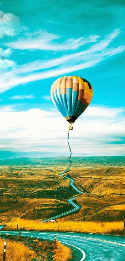 Colorful hot air balloon over scenic winding road under blue sky.