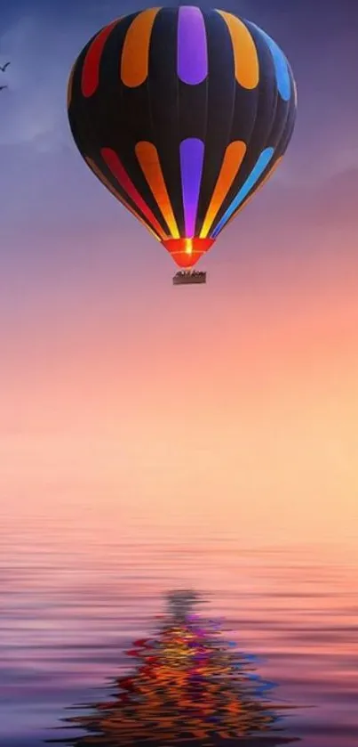 A hot air balloon floats above a colorful sunset reflected on the water.