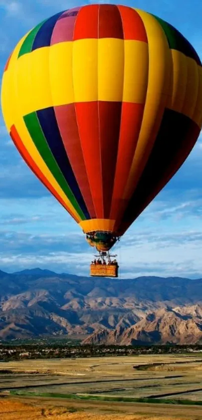 Colorful hot air balloon above mountains and blue sky.