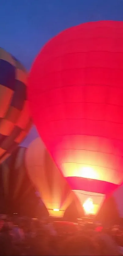 Bright hot air balloons glowing against a deep evening sky.