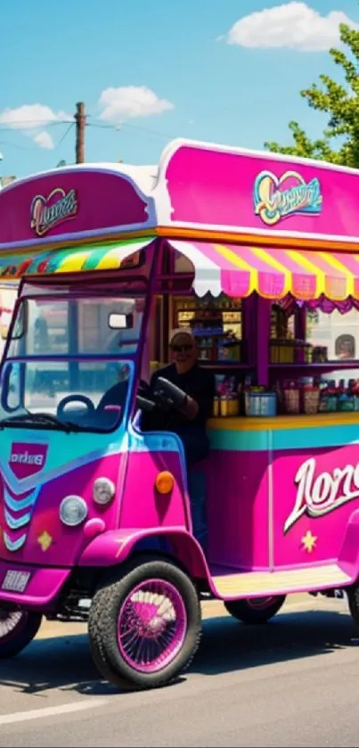 Colorful ice cream cart with vibrant pink and blue design on a sunny street.