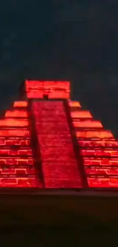 Illuminated pyramid with bright red neon lights against a dark sky at night.