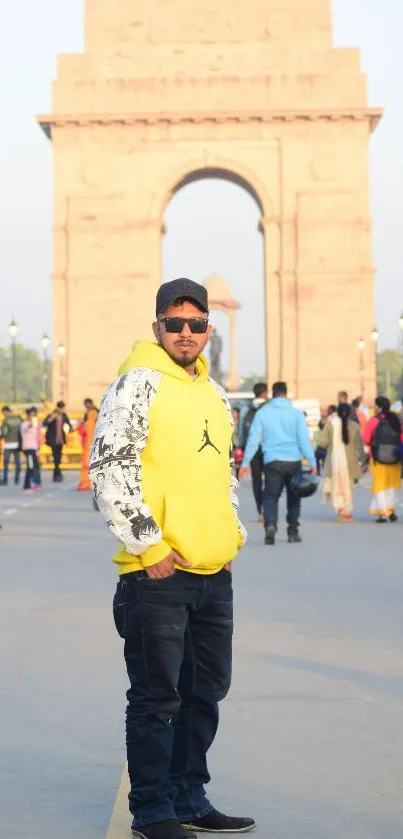 Man stands in front of India Gate with a crowd, vibrant cityscape.