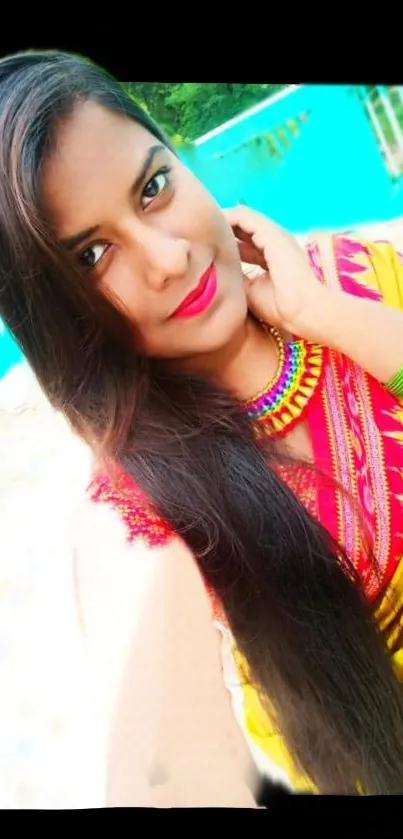 Vibrant woman in colorful Indian attire with turquoise background.