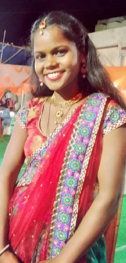 Smiling woman in vibrant Indian traditional dress at festive event.